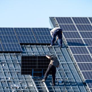 ein Dach wird gedeckt, dabei werden PV-Module angebracht